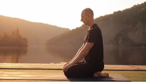 Man meditates by a lake, embodying the serene vibe of Roundry's mindful shaving.